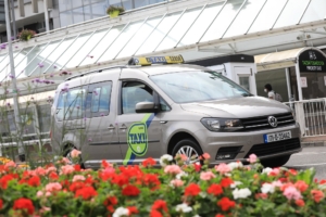 taxi wheelchair accessibile with flowers on road kerb